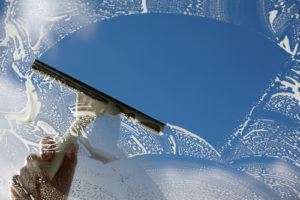 squeegee in hand to clean glass of dirt